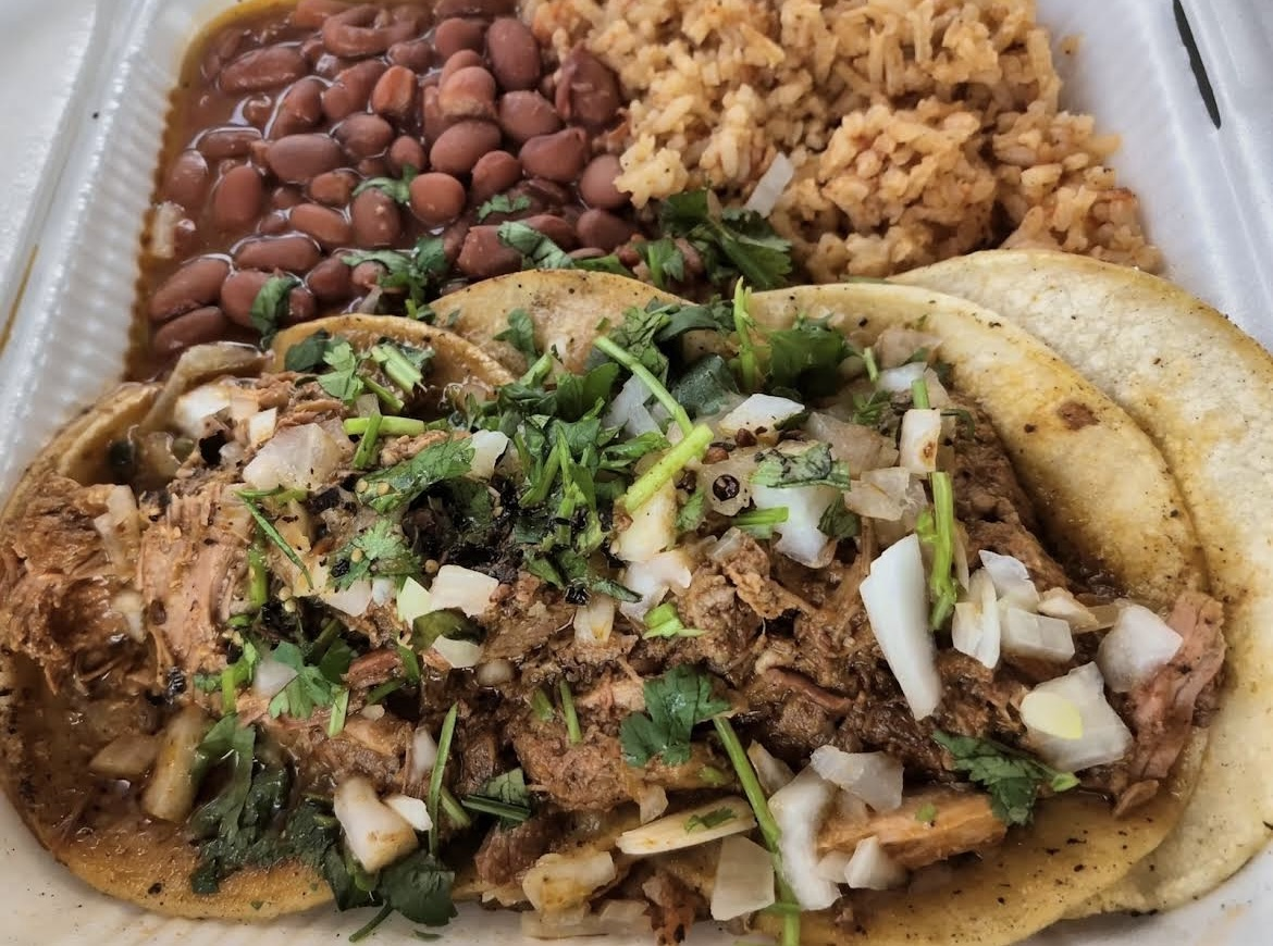 Three street-style tacos with cilantro and diced onions served with Mexican rice and pinto beans